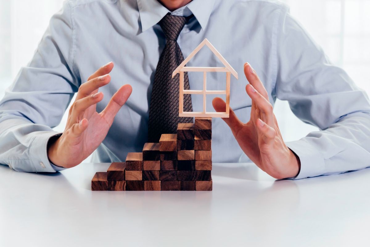 Close up of businessman using hand to protect residential house and real estate building. Concept of protecting, insuring, mortgage, loan, business finance and real estate